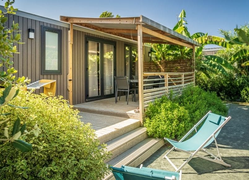 Vue extérieure d'un hébergement mobil-home avec terrasse en bois et transats au camping Les Pirons aux Sables d'Olonne